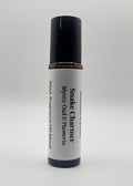 Fragrance oil roll-on labeled 'Snake Charmer' with black and white design on a light gray background