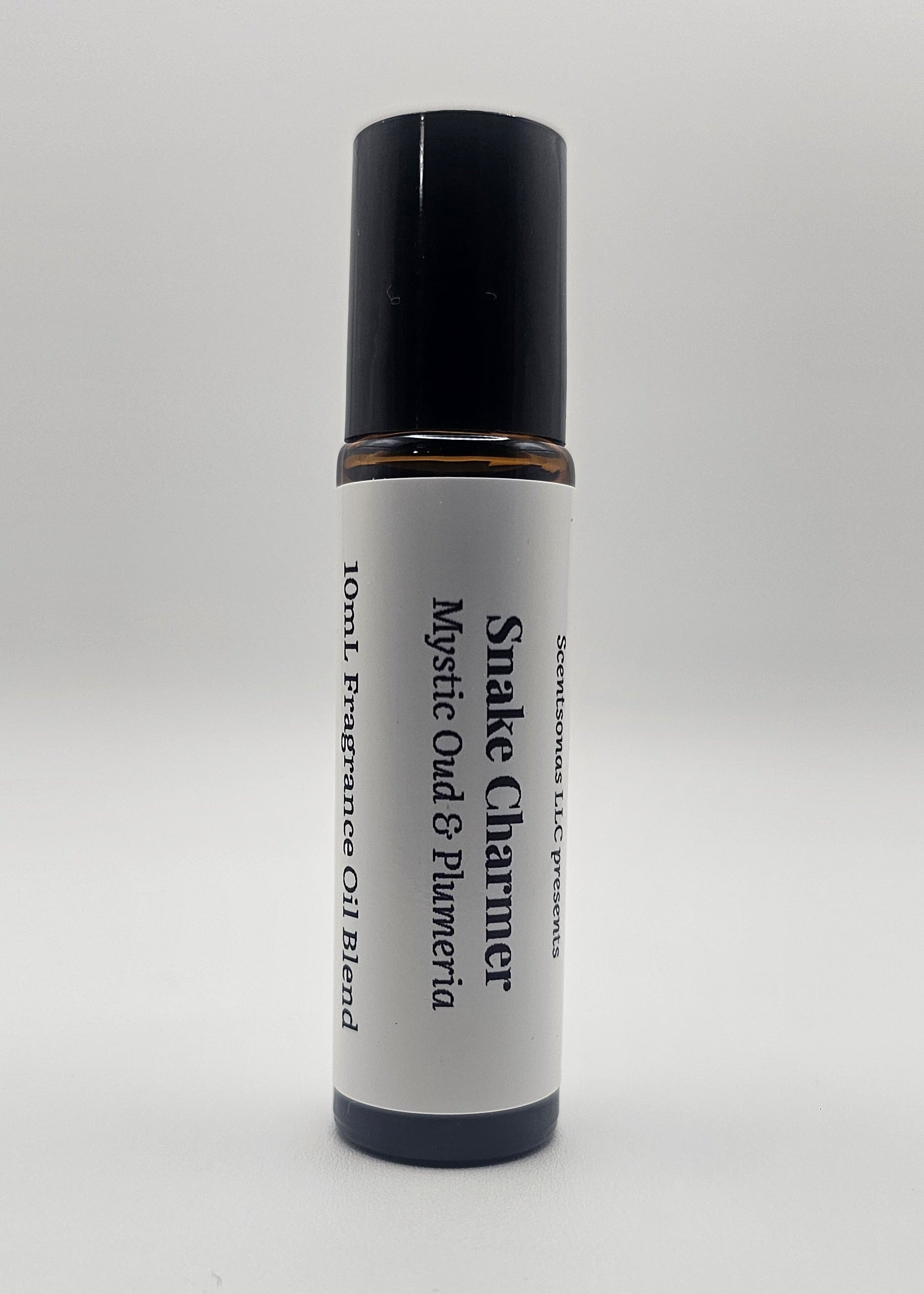 Fragrance oil roll-on labeled 'Snake Charmer' with black and white design on a light gray background